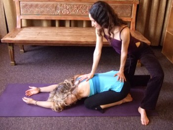 Abelson assists a yoga student in Child's Pose