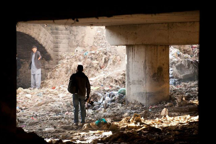 Journalist Wakil Kohsar photographing drug addicts under the bridge, captured by Mo Scarpelli